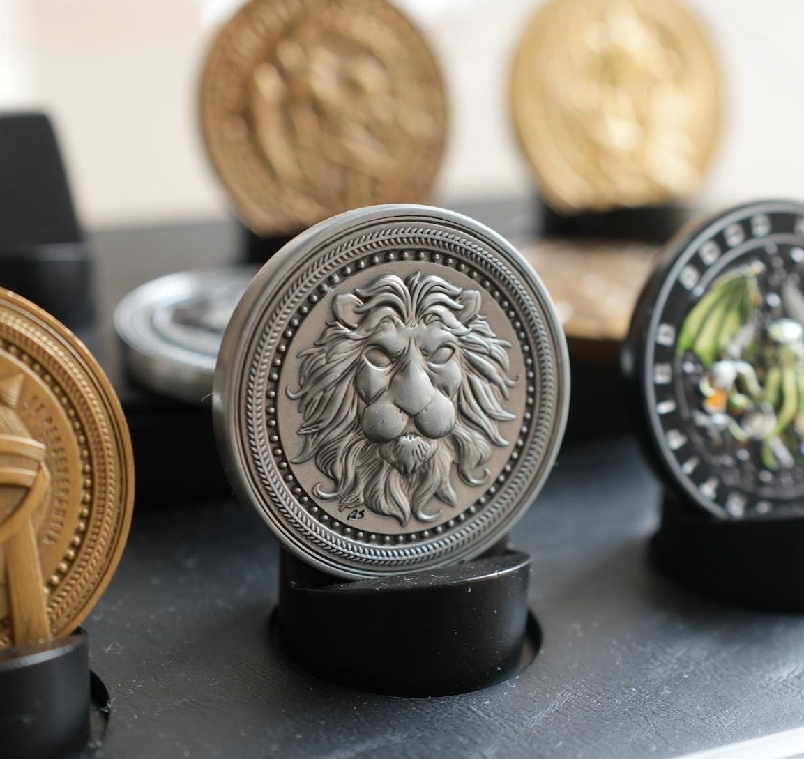 Decorative metal coins with embossed designs on a reflective surface.