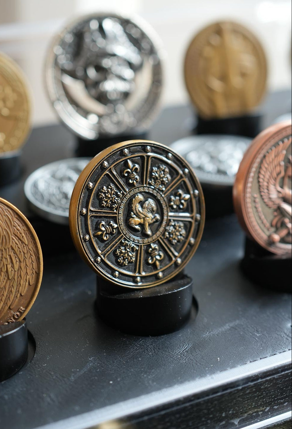 Collection of decorative coins on a reflective surface with a blurred background