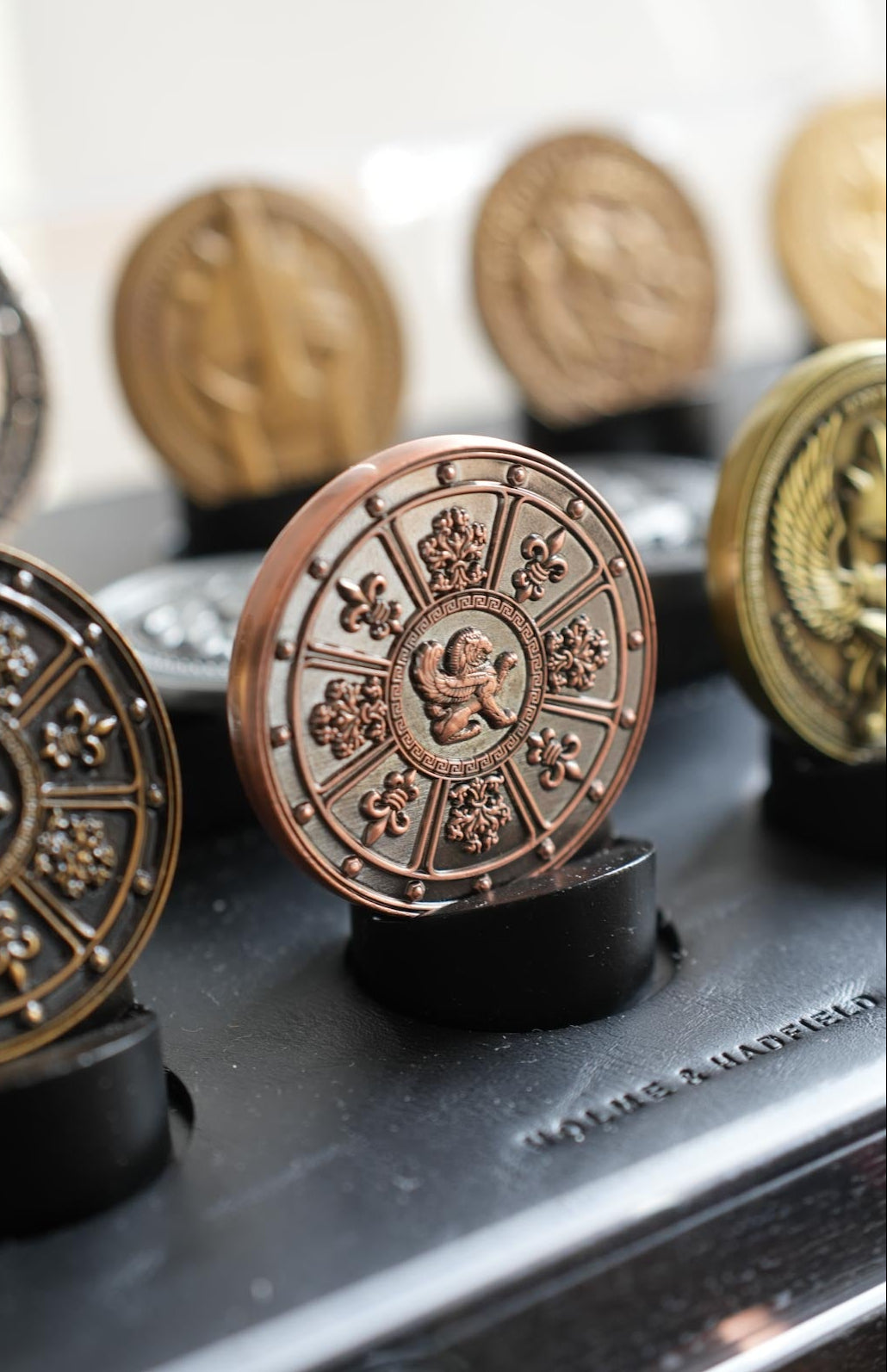 Decorative coins with intricate designs on black stands against a blurred background