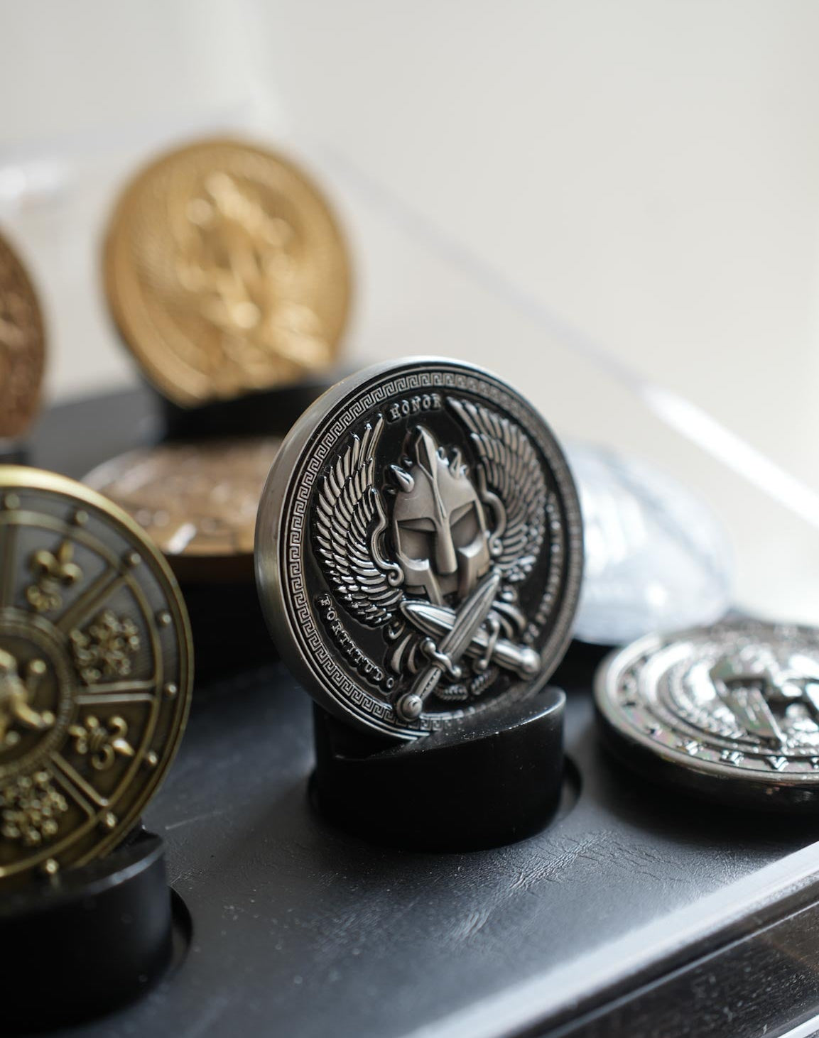 Collection of decorative coins with intricate designs on a reflective surface.