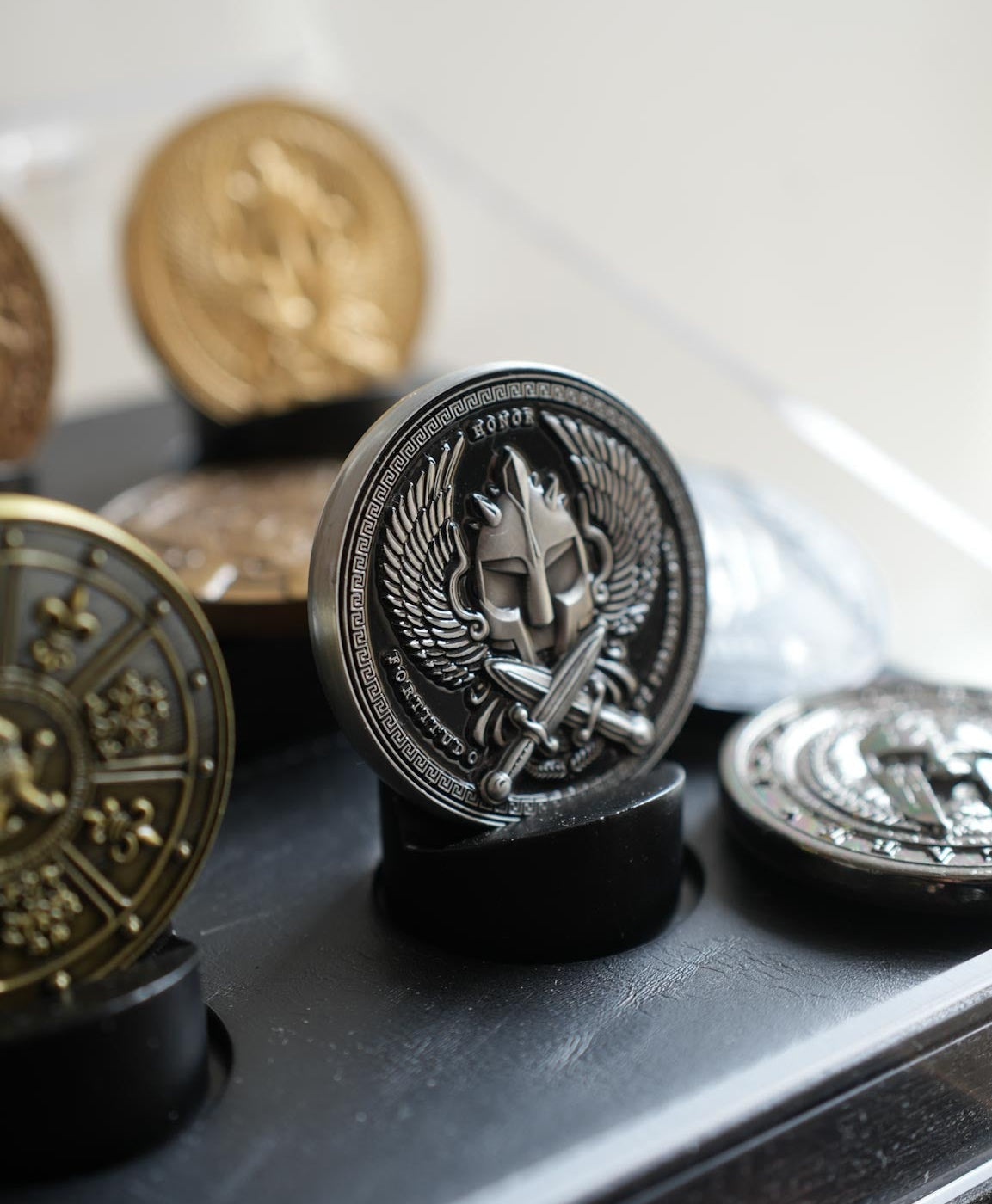 Collection of decorative coins with intricate designs on a reflective surface.