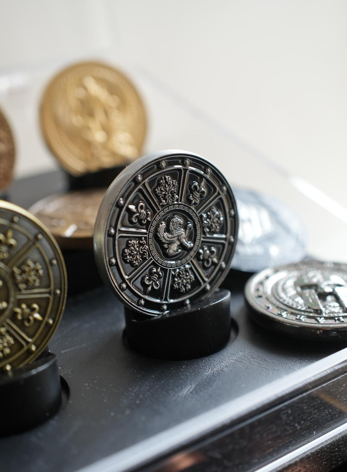 Decorative coins with intricate designs on a reflective surface